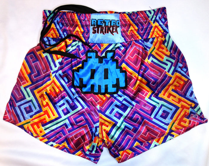 Retro Grappler’s Puzzle Muay Thai Shorts feature a vibrant geometric maze in pink, orange, yellow, blue, and purple, a RETRO STRIKER waistband label, and a blue pixelated alien graphic on the front.