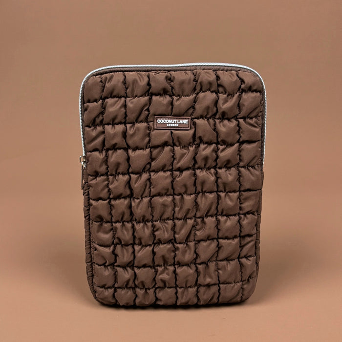 Quilted brown iPad sleeve with visible padding and a Coconut Lane label, displayed on a plain brown background.