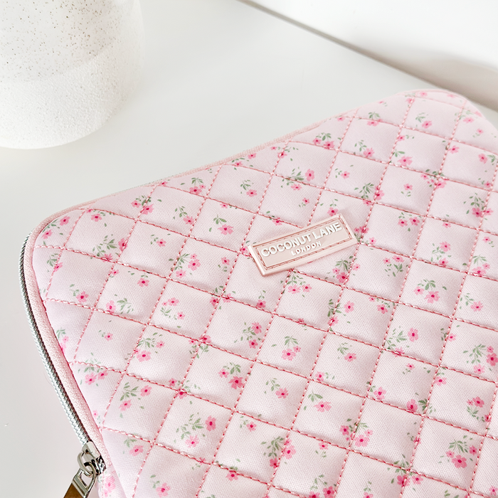 Pink quilted iPad sleeve with a ditsy floral pattern by Coconut Lane, displayed on a white surface.