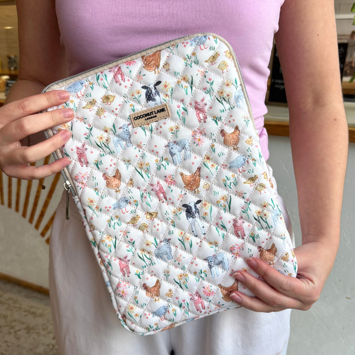 Quilted Coconut Lane iPad sleeve with white animal and floral print, held by a person wearing a pink top.