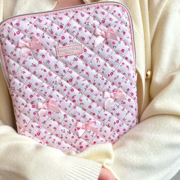 Cream sweater-wearing person holding a pink quilted iPad sleeve with watercolour floral design.