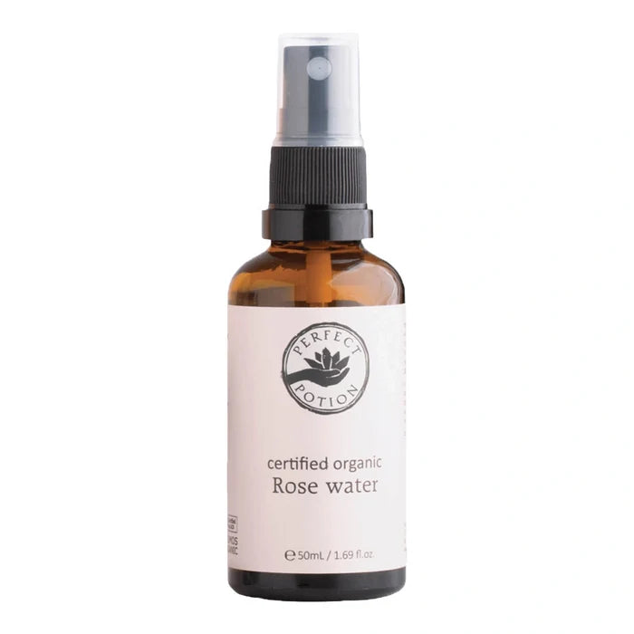 A 50ml amber glass spray bottle of Perfect Potion Certified Organic Rose Water, featuring a white label and a black spray nozzle, set against a plain white background.