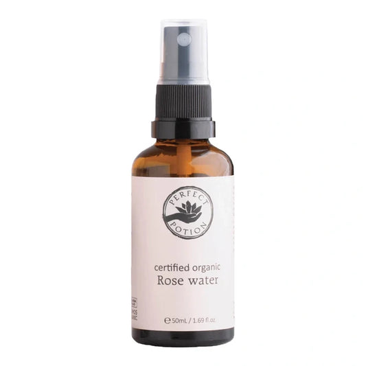 A 50ml amber glass spray bottle of Perfect Potion Certified Organic Rose Water, featuring a white label and a black spray nozzle, set against a plain white background.