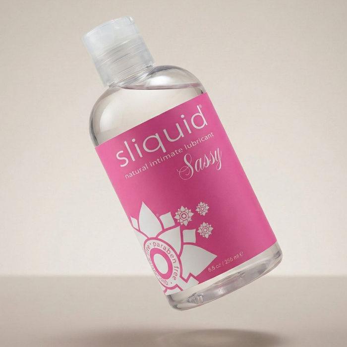Floating perspective shot of the Sliquid Sassy natural intimate lubricant bottle angled over a light surface with a soft shadow below.