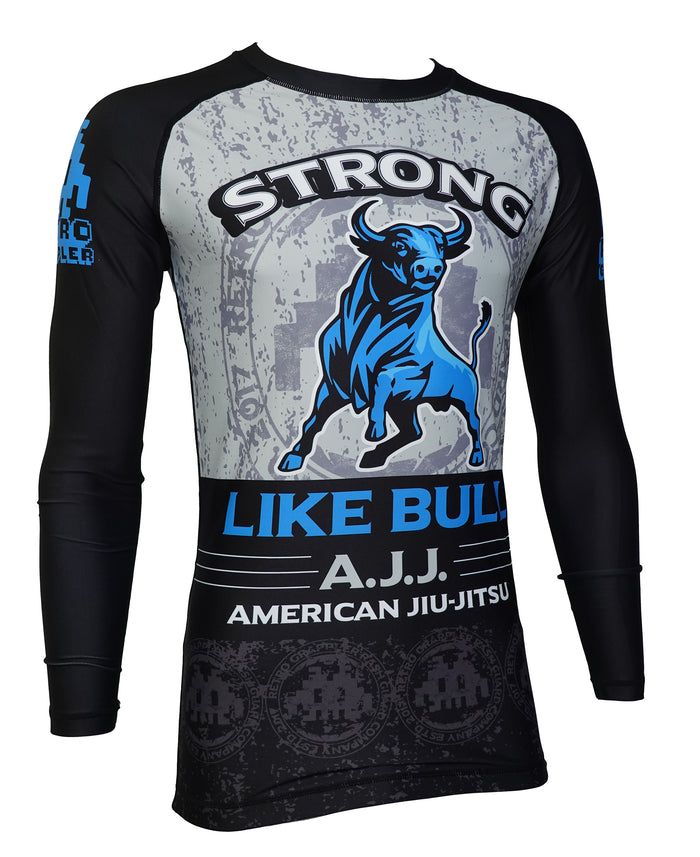 The Retro Grappler Strong Like Bull - Schlitz THE BULL Parody Rash Guard is a long-sleeve black and gray jiu jitsu top with a blue bull graphic, STRONG LIKE BULL, A.J.J., AMERICAN JIU-JITSU, and blue/white MMA accents.