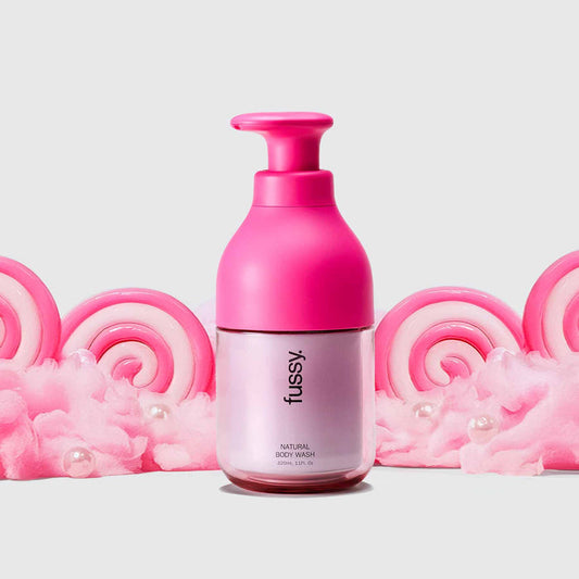 Fussy's Sugar Crush Body Wash Starter pack with Hot Pink refillable bottle set against a backdrop of pink cotton candy.