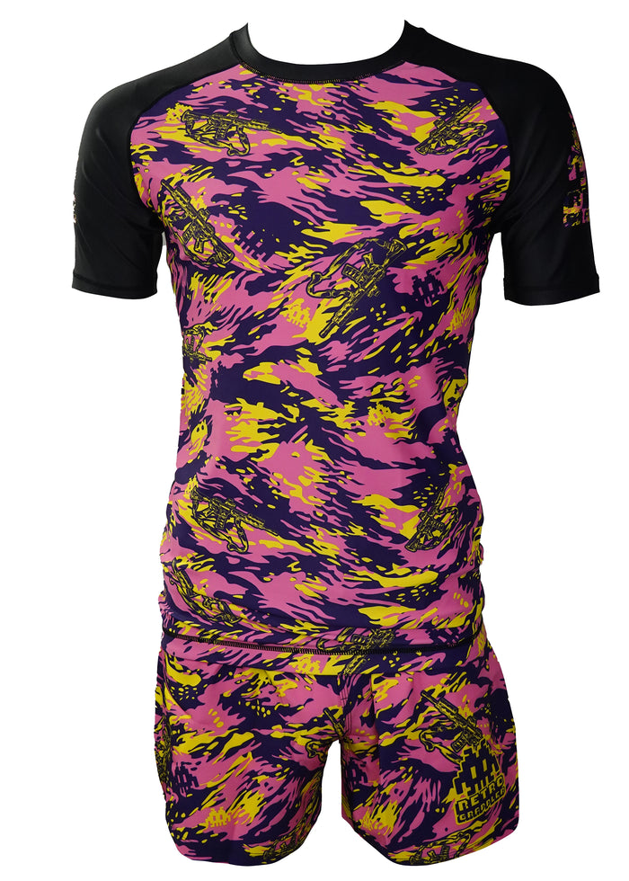 The Retro Grappler Thai Tiger Stripe Camo Kit is a short-sleeve athletic set with matching rash guard and shorts in bold yellow, pink, and purple camo. Dynamic streaks and small graphics give this kit an energetic edge.