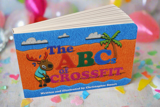 The ABCs of CrossFit Baby Book by Retro Grappler is a colorful childrens book introducing fitness concepts, featuring a cartoon moose and a palm tree on the cover with heart-shaped confetti and balloons in the background.