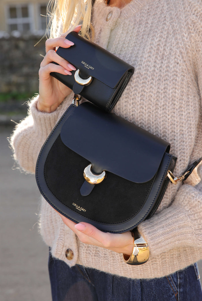 Female model wearing Venetia Black Faux leather Saddle Crossbody and holding matching Letetia Black Medium Purse