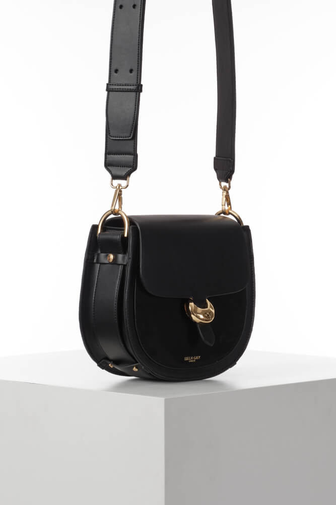 Side view of Venetia Black Faux leather Saddle Crossbody showing the strap detailing around the bottom of the bag and Cannon Street Clasp detail on the front