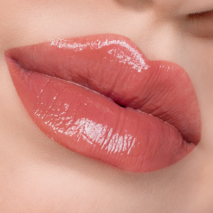 Vibes warm coral lip gloss on lips, light skin tone close-up