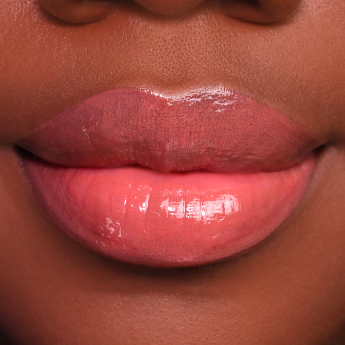 Vibes coral lip gloss on lips, medium-deep skin tone