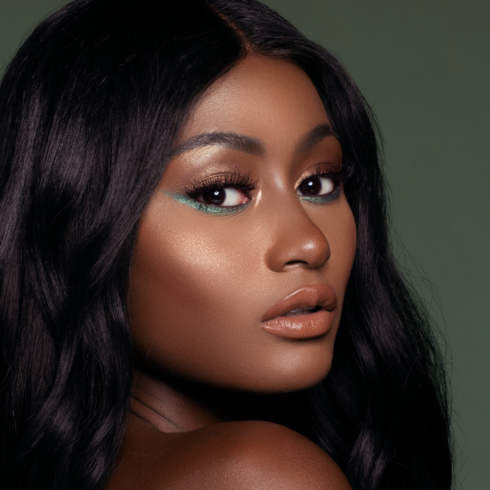 Model wearing Vibes lip gloss with a bronze glam look, deep skin tone
