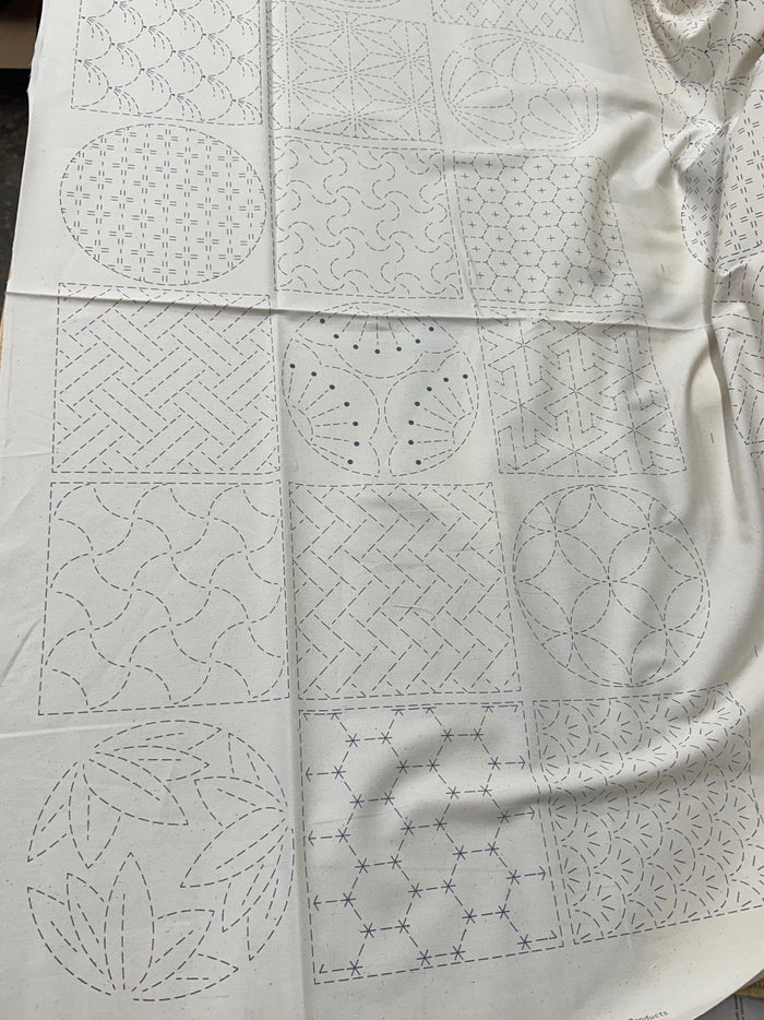 cream colored fabric with sashiko design squares printed on it.