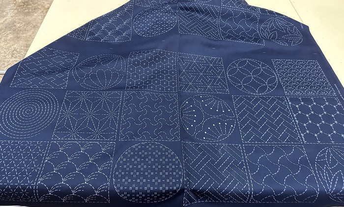 Blue fabric with white geometric sashiko patterns on a flat surface
