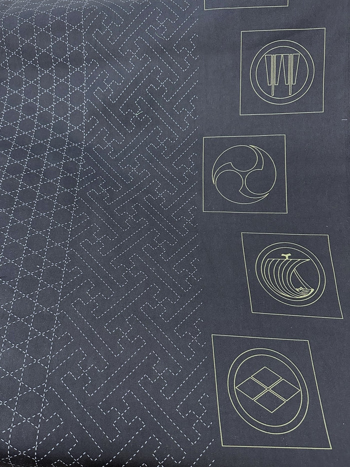 Dark fabric with white geometric sashiko patterns and symbols
