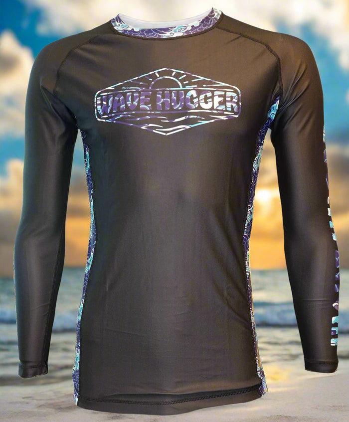 The Wave Hugger Japanese Wave Rash Guard is a black, long-sleeve unisex lycra top with purple and blue trim, offering fast-drying sun protection and WAVE HUGGER on the chest, shown against a beach sunset.