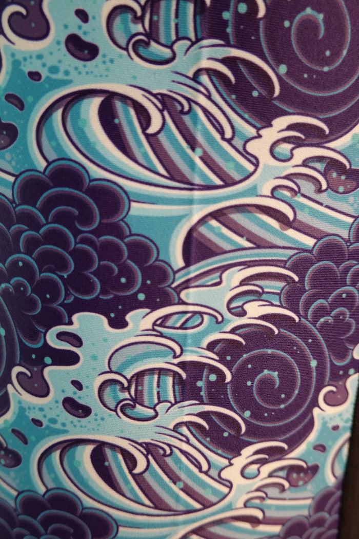 The Wave Hugger Japanese Wave Rash Guard by Wave Hugger features an abstract pattern of swirling blue, purple, and white waves and clouds. Made from fast-drying lycra, this unisex rash guard offers comfort and added sun protection.