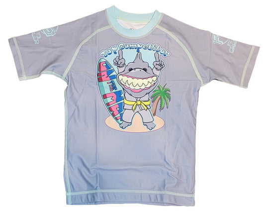 The Retro Grappler Youth - Competition Shark shirt is a light purple, fitted short sleeve featuring a cartoon shark in sunglasses flashing two fingers beside a surfboard and palm tree, with Top Competition above.