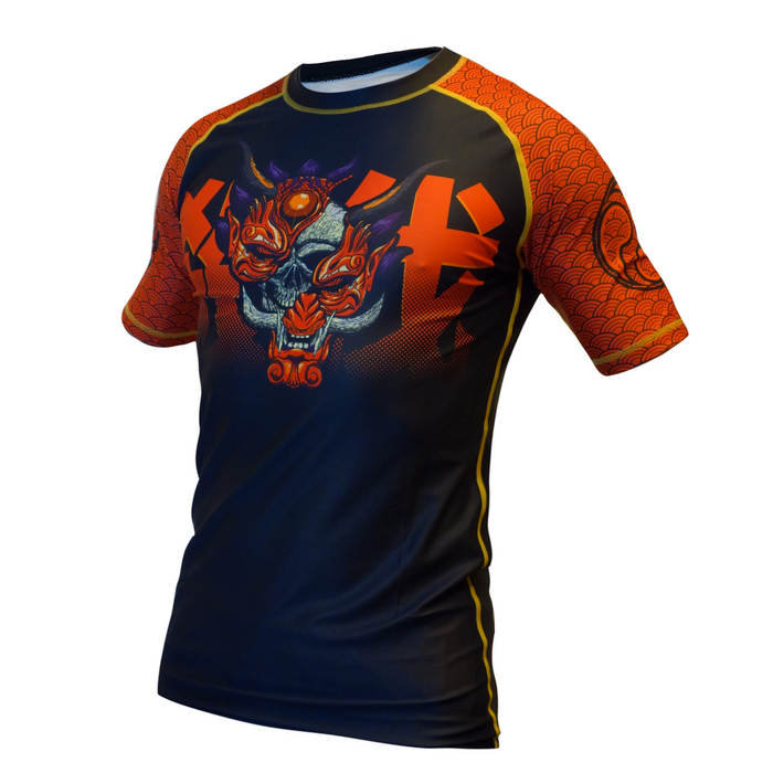 The Retro Grappler Youth - Savage Oni Mask Rashguard features orange wave-patterned sleeves, a black body, and a bold dragon and skull graphic with vibrant orange and blue Yakuza-inspired accents on the chest.